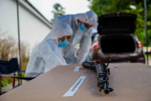 na pierwszym planie bron w tle technicy kryminalistyki