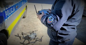 policjant oraz policyjny dron obok radiowozu