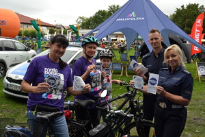 Policjantka, policjant i uczestnicy pikniku trzymają w ręku ulotki