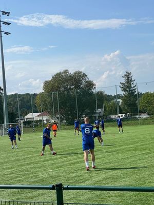 Mężczyźni w strojach sportowych na boisku podczas rozgrzewki.