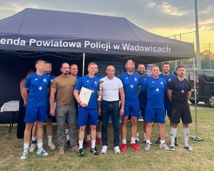 Mężczyźni w strojach sportowych odbierają puchar.