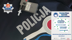 Alcosensor wraz z tarczą do zatrzymywania samochódów na tle napisu policja wraz z logo KPP Sucha Beskidzka, po lewej górnej stronie zdjęcia.