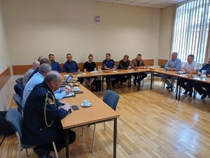 Policjanci oraz przedstawiciele Urzędu Miasta Krakowa siedzący przy stołach podczas spotkania.