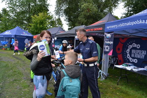 Policjant wręcza ulotki uczestnikom pikniku