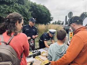Rodzina z dzieckiem przy stoisku policyjnym.