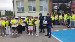 Policjanci rozdaja dzieciom ulotki informacyjne.