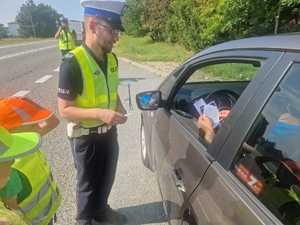 Policjant podczas kontroli węcza ulotki kierowcą.