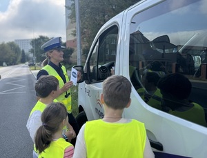 Policjanta i dzieci rozdają ulotki.