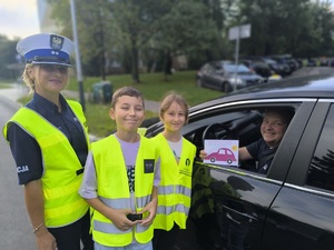 Policjantka i dzieci pozują do zdjęcia z kierowcą.