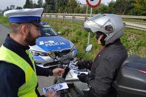 Policjant wręczający materiały profilaktyczne motocykliście