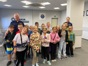 Zdjęcie grupowe w Komendzie Powiatowej Policji w Chrzanowie na zdjęciu stoją dzieci oraz umundurowani funkcjonariusze.