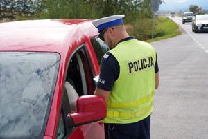 Policjant kontrolujący czerwony samochód