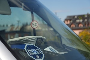 Przednia szyba radiowozu z naklejona naklejką z napisem Mistrzu zwolnij