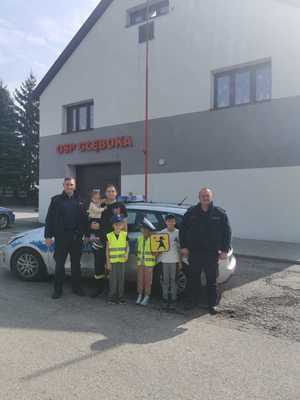 umundurowani policjanci przed radiowozem z uczestnikami warsztatów