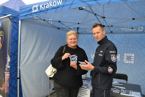 Policjant wraz z kobietą trzymają w ręku ulotki