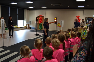 Policjantka pokazując sygnalizator świetlny omawia przepisy ruchu drogowego dzieciom