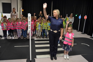 Policjantka pokazuje dzieciom zasady rozglądania się przed przejściem przez jezdnię