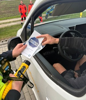 Kampania Mistrzu zwolnij i Road Safety Days  policjant wręcza ulotkę kierowcy