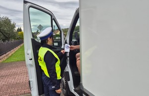 Kampania Mistrzu zwolnij i Road Safety Days   policjant wręcza ulotkę kierowcy dostawczaka