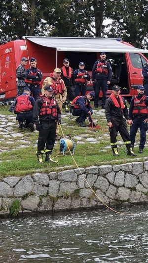 Policjanci ubrani w kamizelki ratunkowe nad brzegiem dunajca