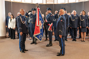 Pożegnanie mł. insp. Dominika Jurczaka ze sztandarem jednostki. W tle kadra kierownicza i goście.2
