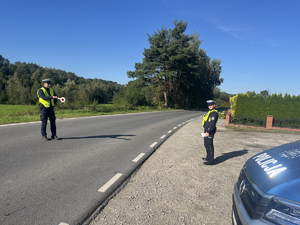 policjant ruchu drogowego z tarczą do zatrzymywania pojazdów wskazuje kierowcy miejsce zatrzymania