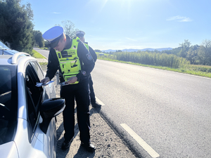 policjant wręczający ulotki kierowcy samochodu osobowego