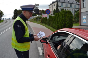 Policjant wręczający broszury informacyjne
