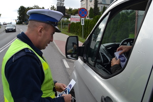 Policjant wręczający ulotke informacyjną