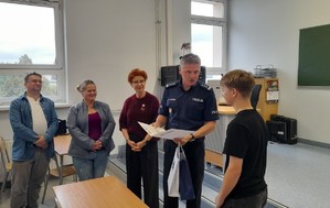 Komendant wręcza Konradowi list pochwalny i nagrodę obok pani dyrektor i rodzice