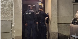 policjanci pred klatką schodową dzwonią domofonem