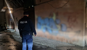 policjant patroluje osiedle, na ścianie graffiti