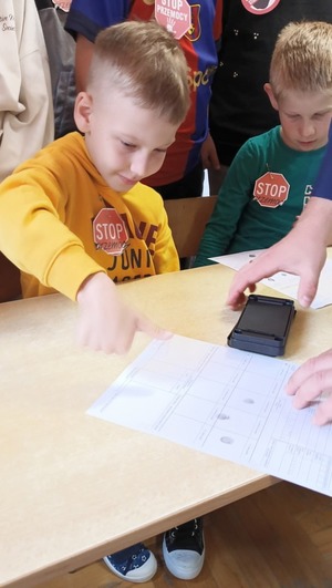 Uczniowie podczas pobierania odcisków palców