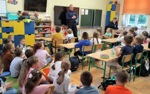 Umundurowani funkcjonariusze oraz uczniowie biorący udział w prelekcji
