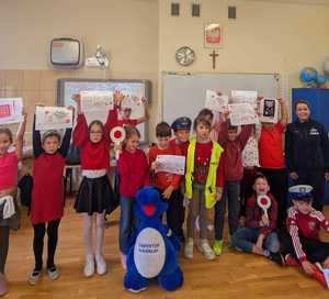 pamiątkowe zdjęcie uczniów z policjantką i maskotką policyjną