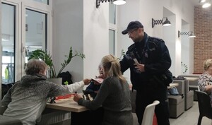Policjant rozdaje ulotki seniorom