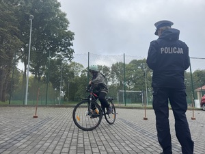 Policjantka nadzoruje dziecko na rowerze na egzaminie praktycznym
