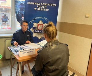 policjantka rozmawiająca z kobietą przy stoisku informacyjnym w powiatowym urzędzie pracy