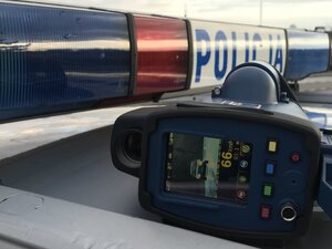 miernik prędkości leżący na dachu oznakowanego radiowozu, przy lampie błyskowej
