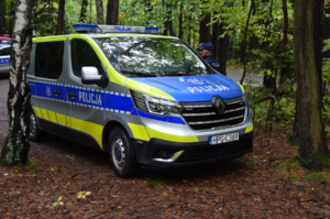 Oznakowany radiowóz policyjny oraz stojący obok funkcjonariusze