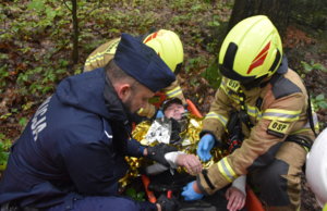 Policjant oraz strażacy podczas czynności z odnalezionym mężczyzną