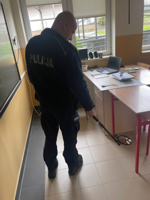 Policjant podczas czynności w klasie poszukuje ładunku wybuchowego