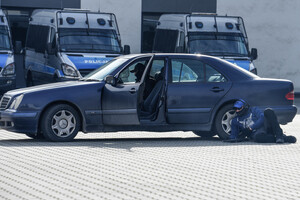 policjant grający zamachowca leżący przy samochodzie