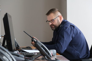 dyżurny przy komputerze z radiostacją w ręce