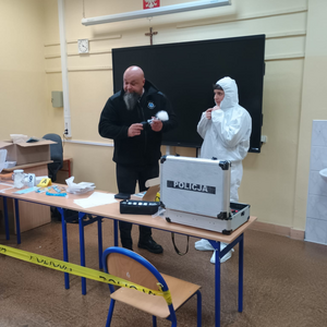 Policjant obok chłopiec w białym kombinezonie