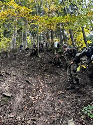 młodzież w mundurach schodzą z góry w lesie
