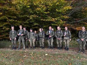 uczniowie w mundurach podczas zbiórki trzymają w rękach ulotki dotyczące handlu ludźmi