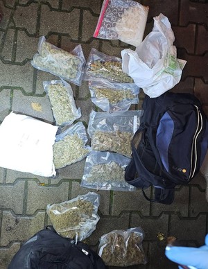 kilka worków foliowych z zawartością suszu roślinnego oraz białej zbrylonej substancji ułożonych na kostce brukowej