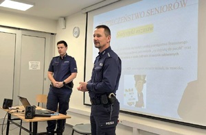 Na zdjęciu widac dwóch umundurowanych policjantów i wyświetlana w tle prezentacje_