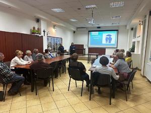 Seniorzy ogladaja preznetacje prowadzaona przez policjantki